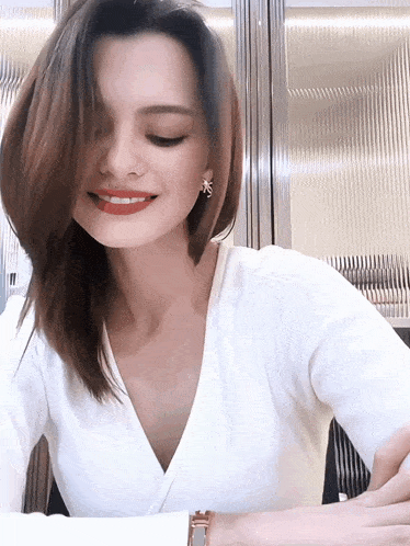 a woman wearing a white shirt with a plunging neckline smiles