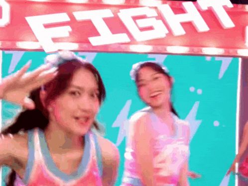 two girls are dancing in front of a sign that says " fight "