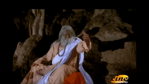 a man with a beard is sitting in a cave with the words babascio written in pink