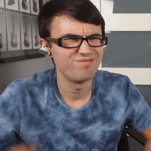 a man wearing glasses and ear buds makes a face