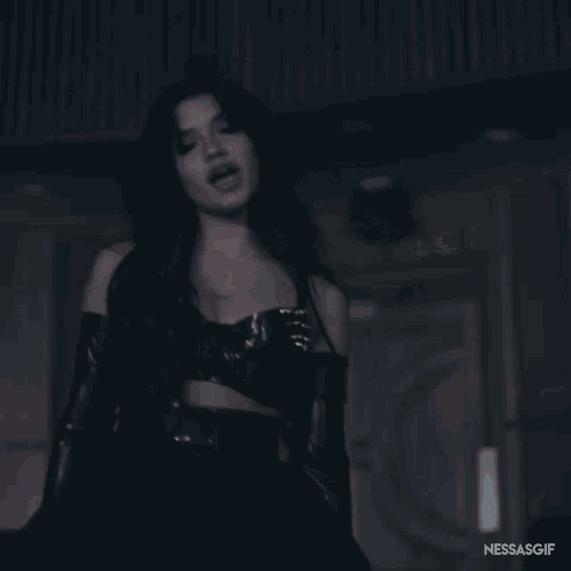 a woman wearing black gloves and a black dress with nessasgif written on the bottom right