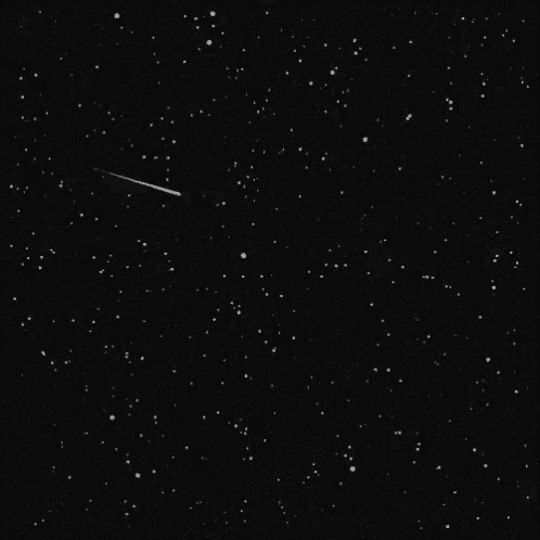 a black and white image of a shooting star in the night sky