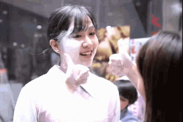 a girl giving a thumbs up sign while talking to another girl