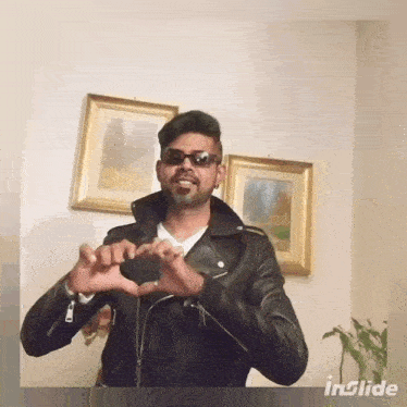 a man in a leather jacket making a heart shape with his hands