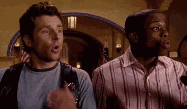two men are standing next to each other in a room and looking at something .