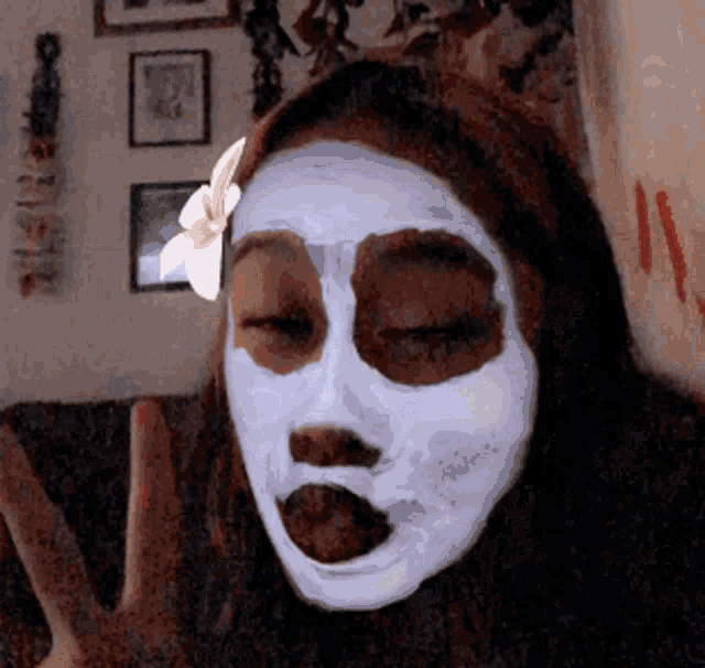 a woman with a white mask on her face is giving the peace sign