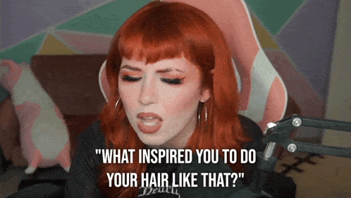 a woman with red hair says " what inspired you to do your hair like that " in front of a microphone