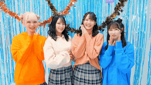 four girls are posing for a picture in front of a blue background