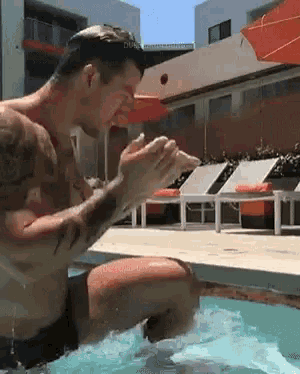 a shirtless man is kneeling in a swimming pool with his hands folded in prayer