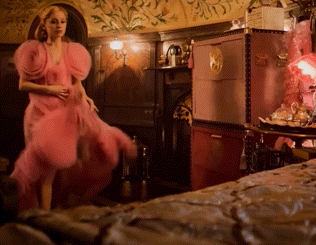 a woman in a pink dress stands in a room