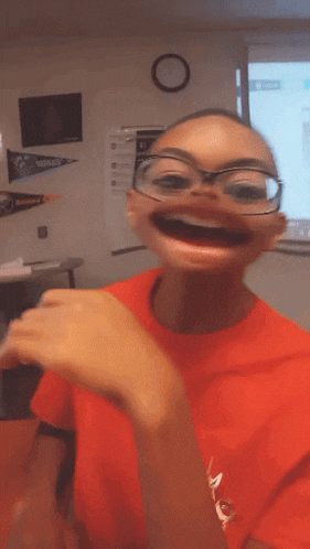 a boy wearing glasses and a red shirt that says king is making a funny face