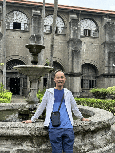 a man stands in front of a fountain in front of an old building
