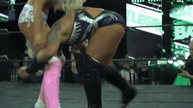 two women are wrestling in a ring with a sign that says battle bay