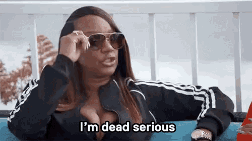 a woman wearing sunglasses is sitting on a couch and saying `` i 'm dead serious ''
