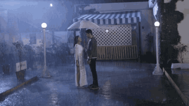 a man and a woman are kissing in the rain under an umbrella