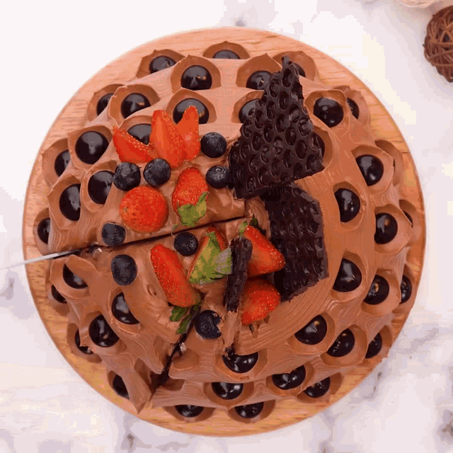 a chocolate cake with strawberries and blueberries on top of it