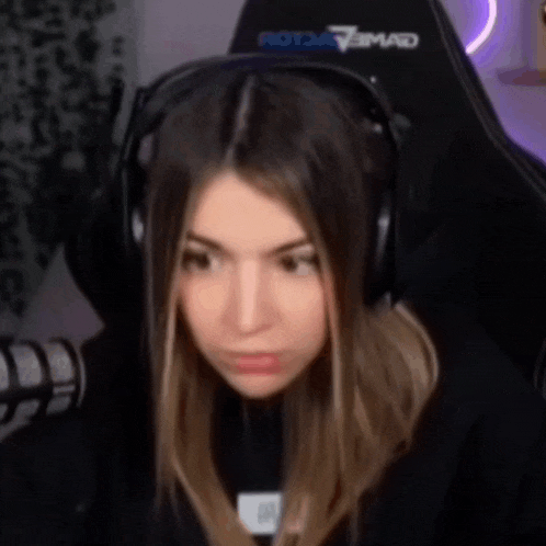 a girl wearing headphones is sitting in a gaming chair .