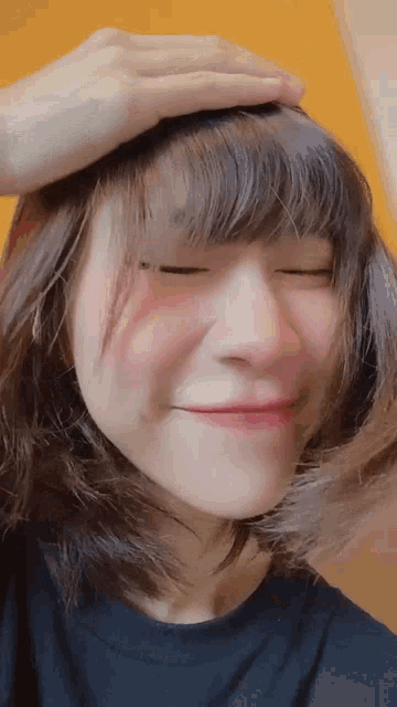 a close up of a woman 's face with a hand on her head .