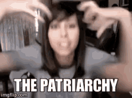 a woman is making a heart shape with her hands and the words " the patriarchy " are visible behind her