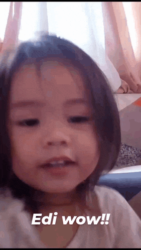 a little girl is making a surprised face and says edi wow !