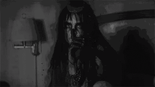 a black and white photo of a woman sitting on a bed with blood on her face .