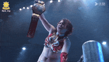 a female wrestler is holding a championship belt above her head in a ring