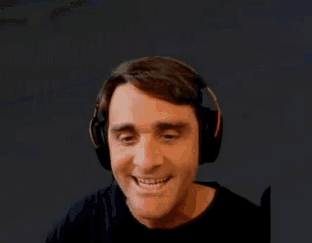 a man wearing headphones is smiling with a blue background