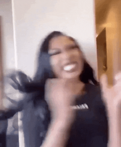 a woman with long black hair is laughing and making a funny face with her hands in the air .