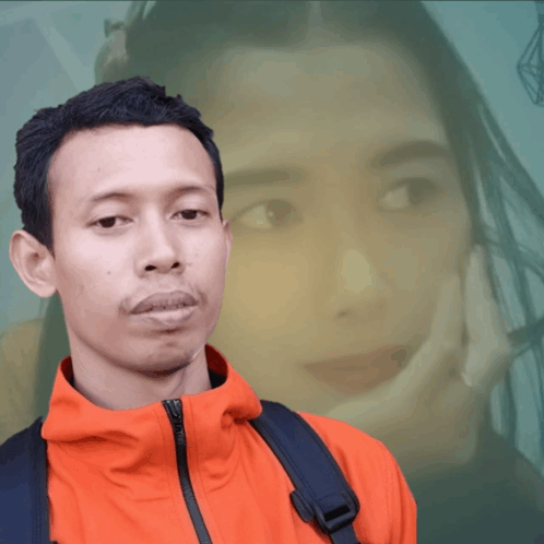 a man in an orange jacket is standing in front of a woman 's face