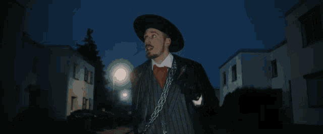 a man with a chain around his neck is standing in front of a street light