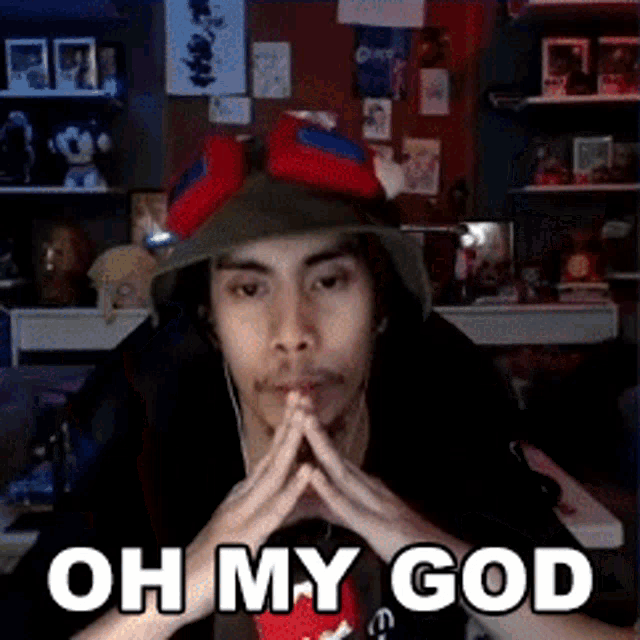 a man wearing a hat and goggles is sitting in front of a computer and says oh my god .