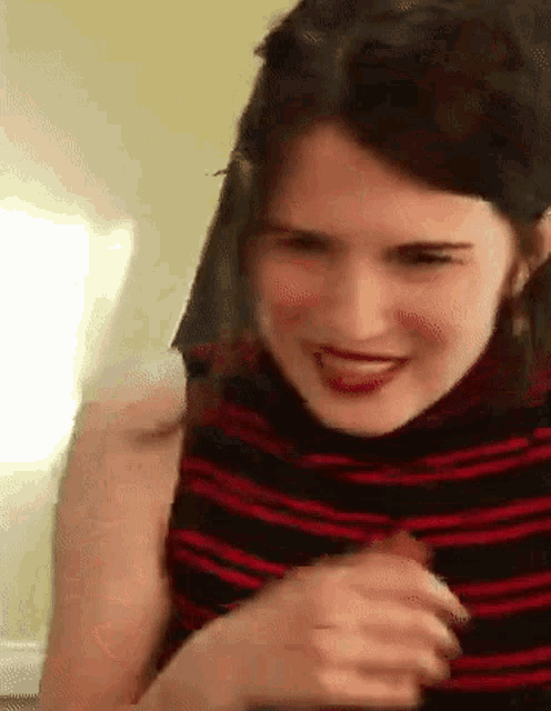 a woman in a red and black striped shirt is smiling and laughing .