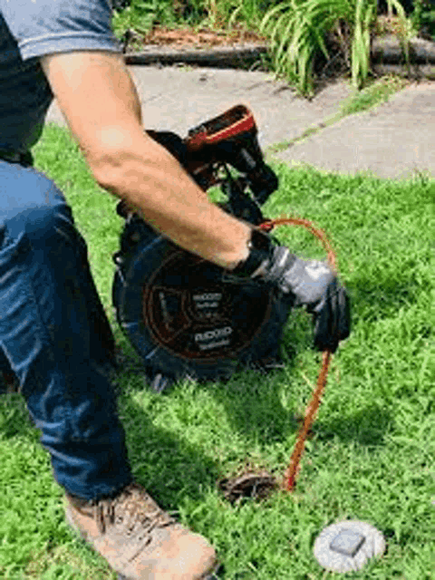 a man is kneeling down in the grass using a camera to look into a hole in the ground .