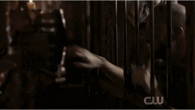 a woman in a dark room with a cw logo on the bottom