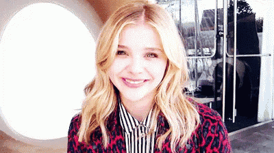 a woman in a leopard print jacket and striped shirt is smiling for the camera .
