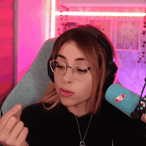 a woman wearing glasses and headphones stands in front of a microphone with a sticker on it that says soda