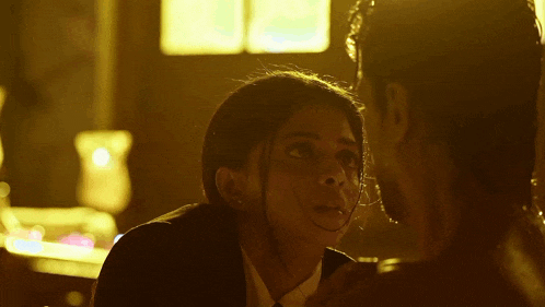 a man and a woman are looking at each other in a room