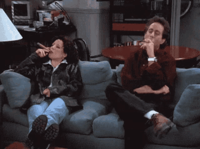 a man and a woman sit on a couch smoking