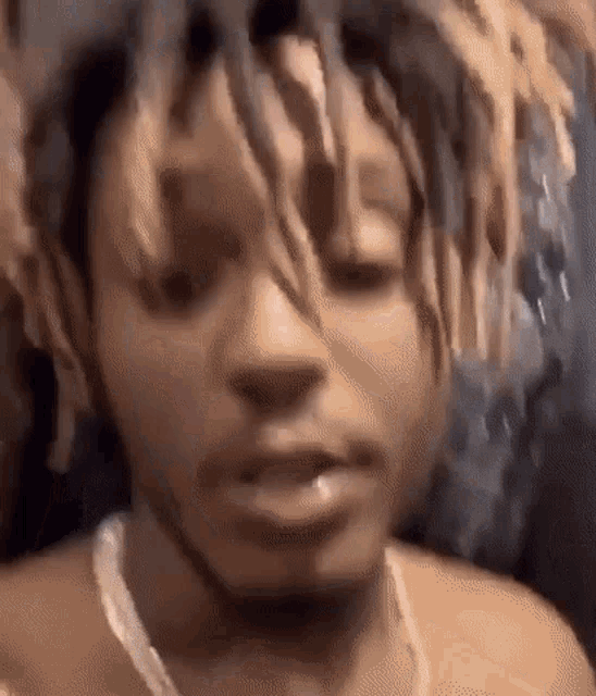 a close up of a man 's face with dreadlocks and a chain around his neck .