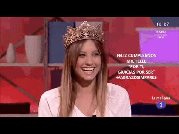 a woman with a crown on her head is smiling on a television screen