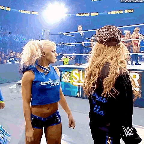 two women are standing next to each other in a wrestling ring .