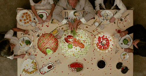 a group of people are sitting at a table with plates of food
