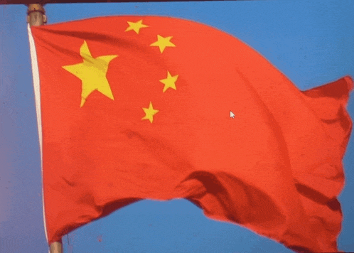 a red flag with yellow stars is flying in the wind against a blue sky