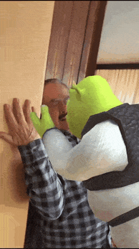 a man in a shrek costume is kissing a man on the cheek