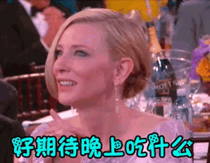 a woman sitting at a table with a bottle of vodka in the background