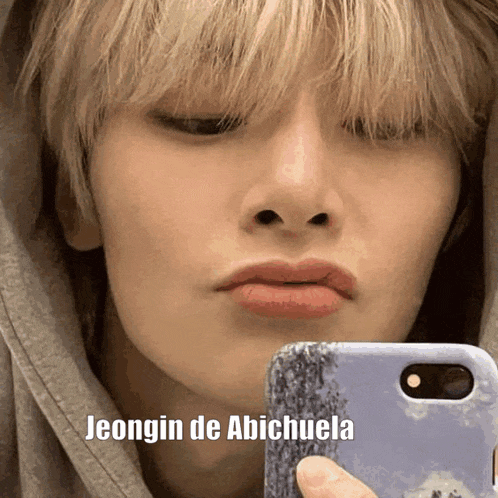 a close up of a person taking a selfie with the words jeongin de abichuela below