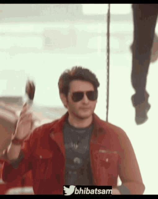 a man wearing sunglasses and a red jacket has a twitter logo on the bottom right