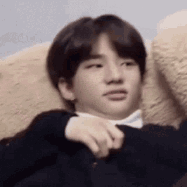 a young man is sitting on a couch with a teddy bear .