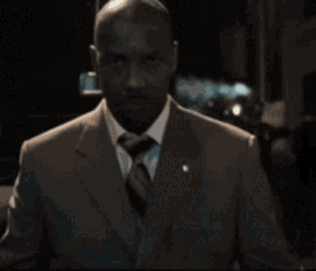 a man in a suit and tie stands in front of a crowd