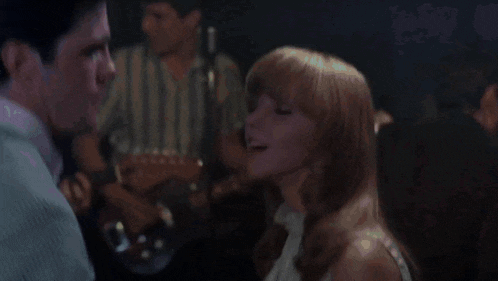 a man in a suit and tie is dancing with a woman